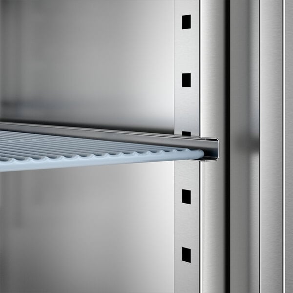 A close-up view of an adjustable wire shelf inside a stainless steel two-section solid door reach-in freezer.
