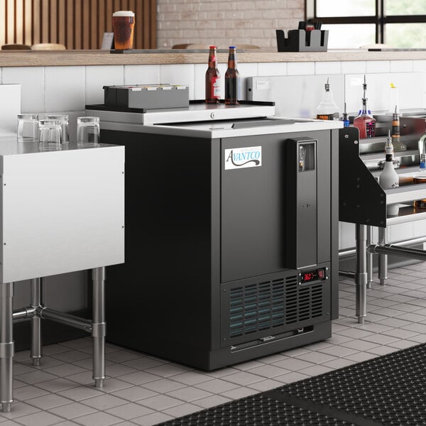 An Avantco black horizontal bottle cooler in a bar.