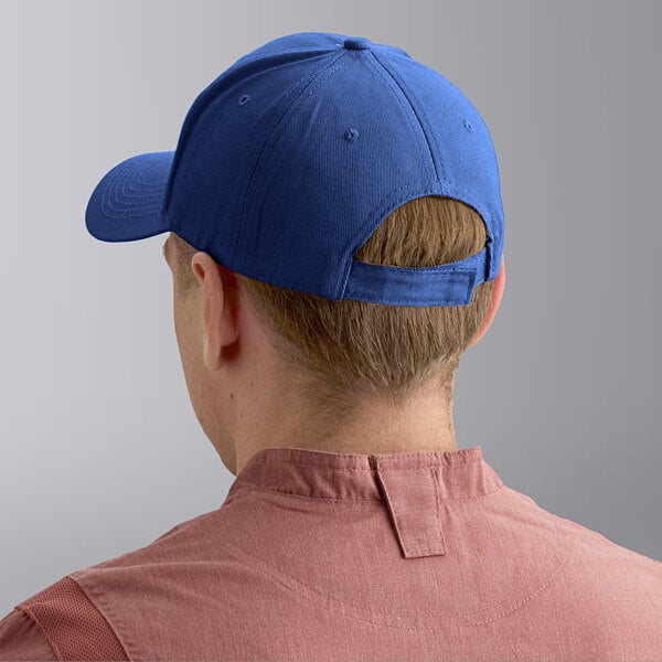 A royal blue 6-panel cap shown from the back, worn by a person in a pink shirt.