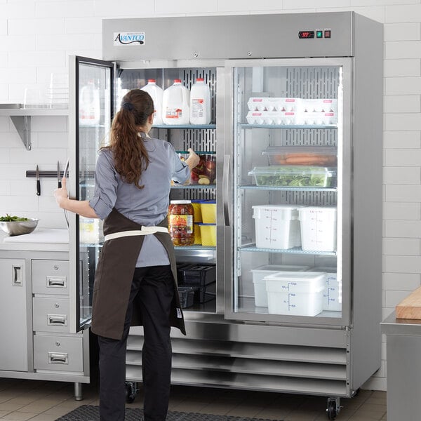 kitchen employee reaching into a glass door refrigerator