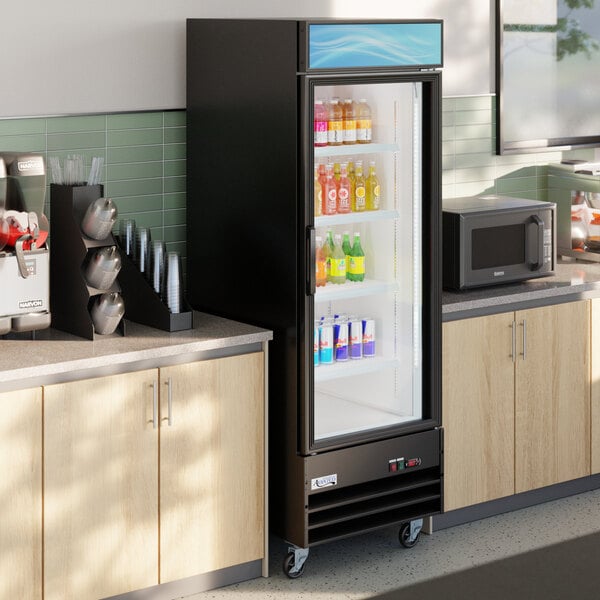 A black glass door merchandiser refrigerator with LED lighting, stocked with assorted beverages and positioned between countertops in a commercial setting.