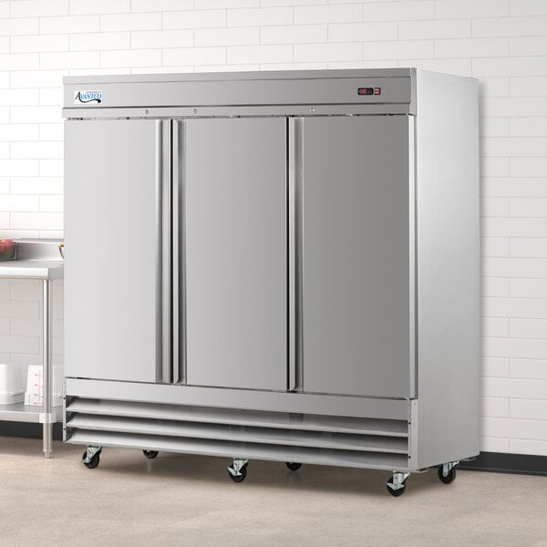 An Avantco stainless steel solid door reach-in refrigerator in a large room.