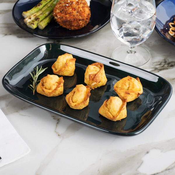 A green GET Cosmo rectangular melamine platter with food on a table.