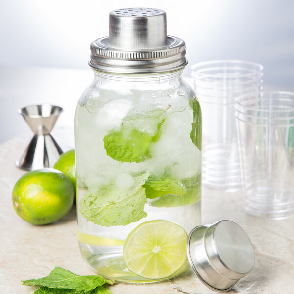 A Tablecraft glass Mason jar cocktail shaker with a lid, ice, and mint leaves.