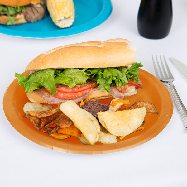 A sandwich and potato chips on a Creative Converting pumpkin spice orange paper plate.