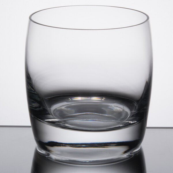 A close-up of a Reserve by Libbey Symmetry Old Fashioned Glass with a small amount of liquid in it.