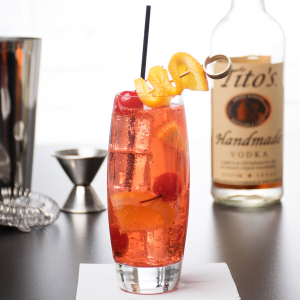 A Reserve by Libbey highball glass filled with a drink and a straw with orange slices and cherries.