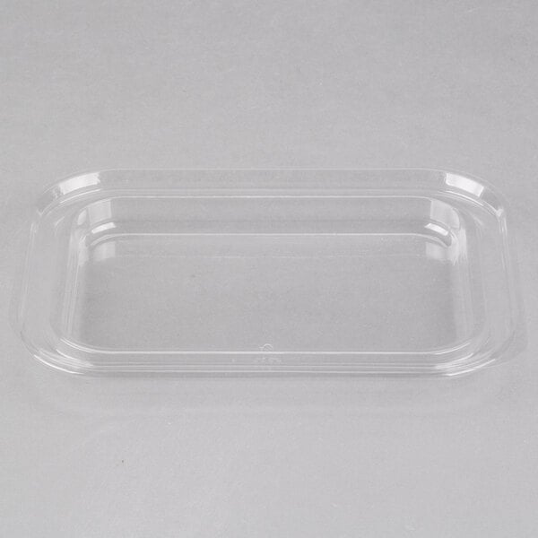 A clear plastic lid on a white surface over a clear plastic tray.