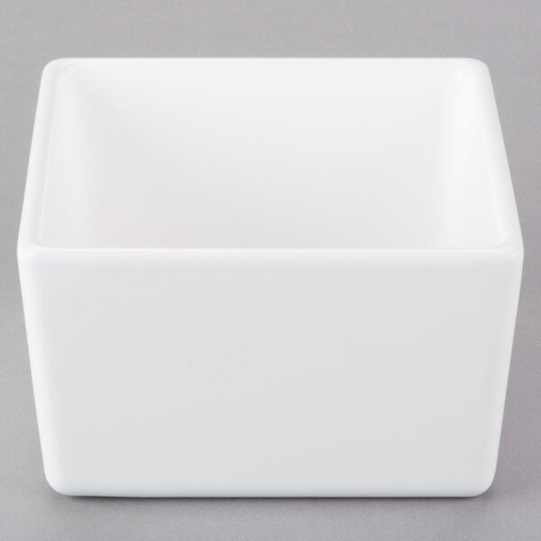 A white square Tablecraft bowl on a gray surface.