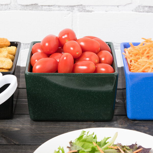 A Tablecraft hunter green bowl with white speckles full of tomatoes on a table.