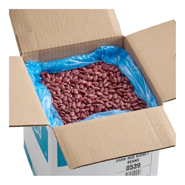 A large open cardboard box lined with a blue plastic bag, filled with dried dark red kidney beans.