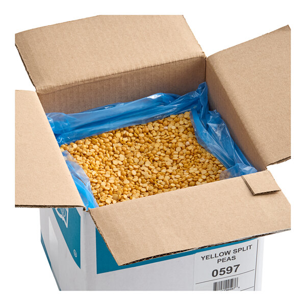 A cardboard box containing 20 pounds of dried yellow split peas lined with a blue plastic bag.