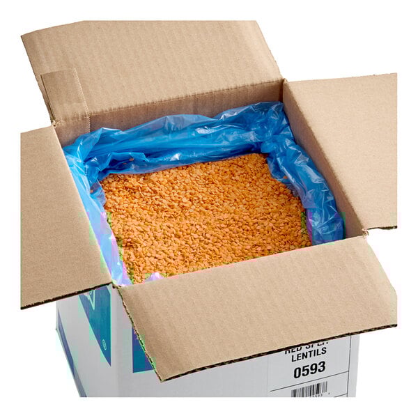 A cardboard box containing 20 pounds of dried red split lentil beans lined with a blue plastic bag.