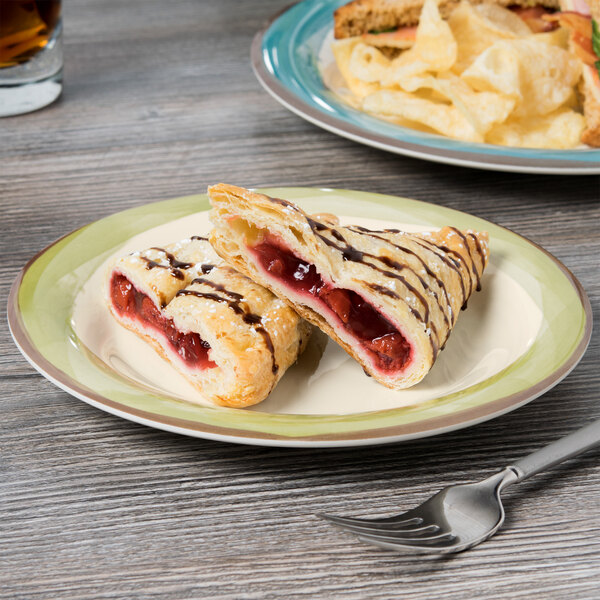 A Kanello ivory melamine plate with two pastries and a fork on it.