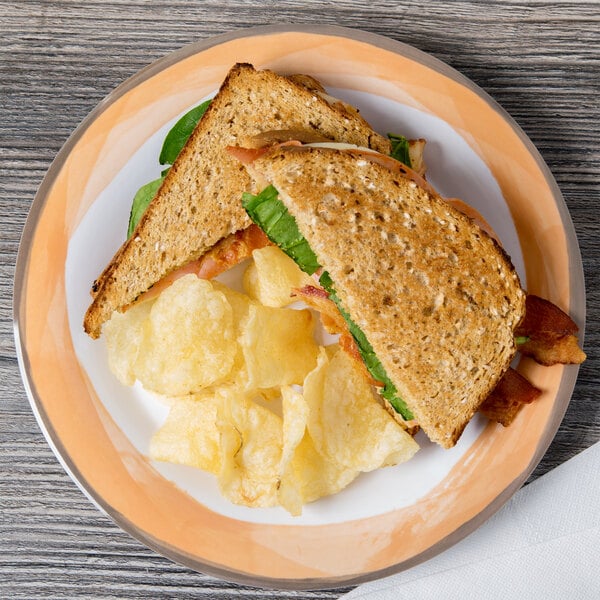 A Kanello Diamond White melamine plate with a sandwich, potato chips, and bacon on a wood table.