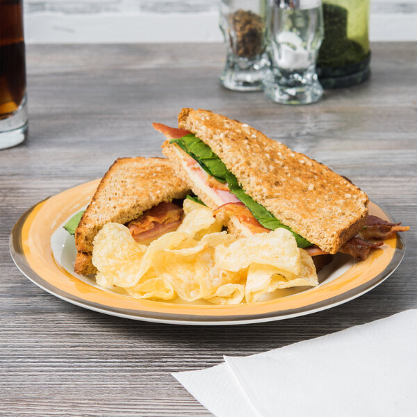 A Kanello ivory melamine plate with a wide yellow rim holding a sandwich with bacon and potato chips.