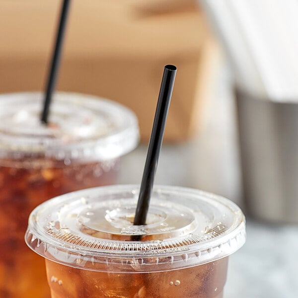 Two plastic cups with ice and Choice black wrapped straws on a table.