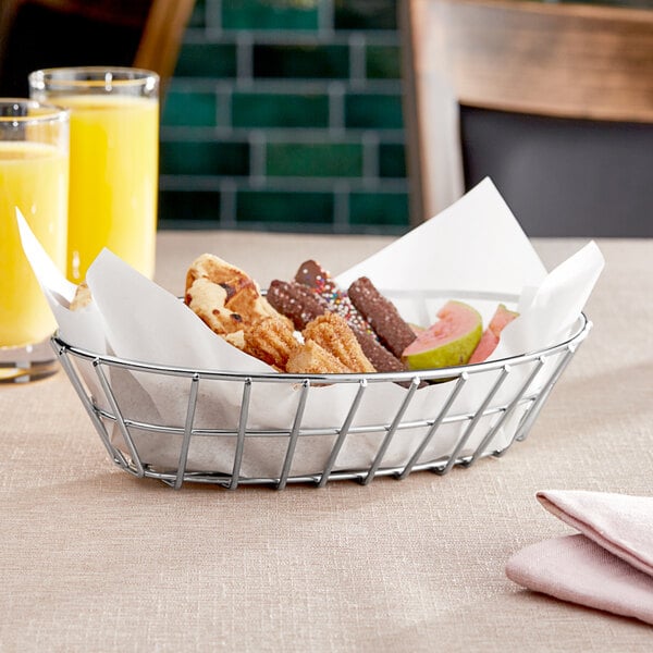 A Clipper Mill chrome oval grid basket filled with food on a table.