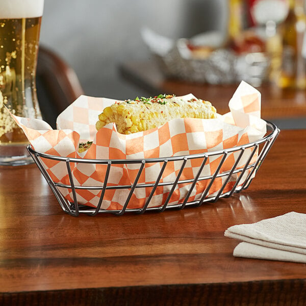 A Clipper Mill stainless steel oval grid basket with corn on the cob in it.