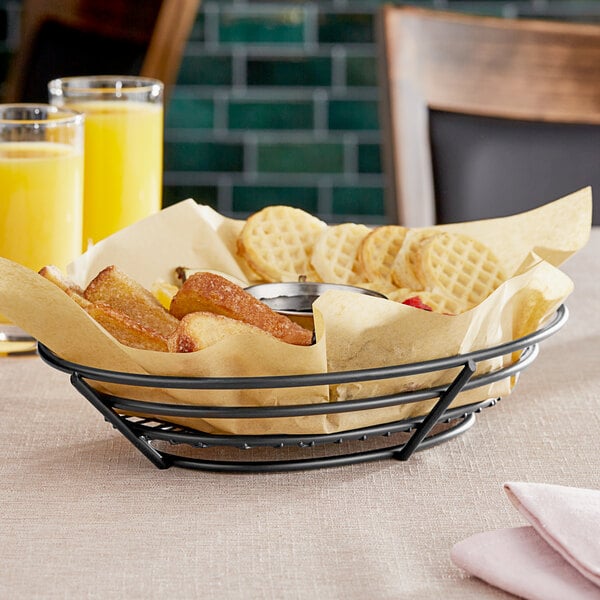 A Clipper Mill black iron oval basket of food on a table.