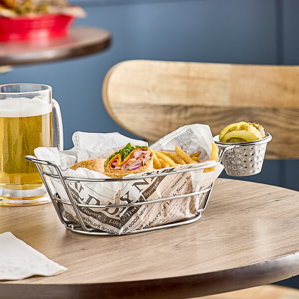 A Clipper Mill stainless steel oval basket filled with food and a beer on a table.