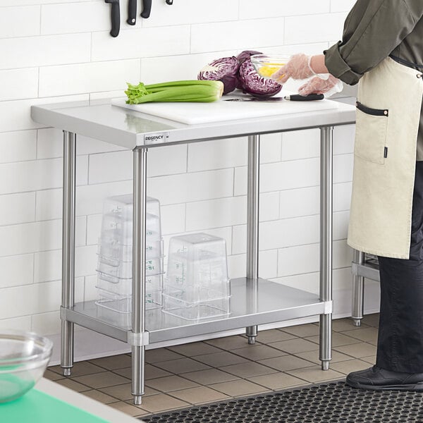 A woman in a white coat cutting vegetables on a Regency stainless steel work table with an undershelf.