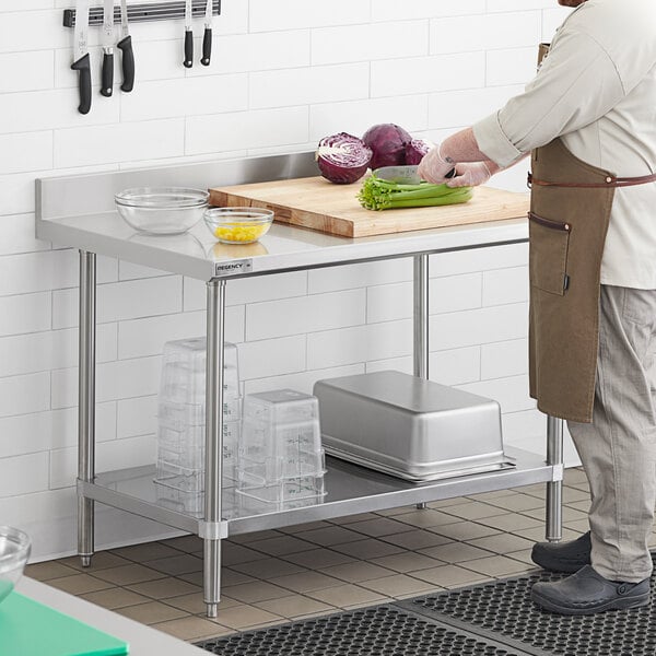 A man cutting vegetables on a Regency stainless steel work table with undershelf.