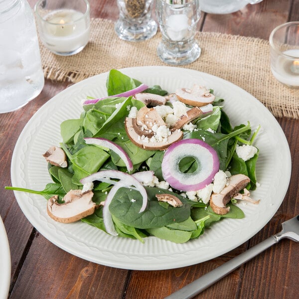 An Ivory (American White) china plate with a salad of spinach, mushrooms, onions, and cheese.