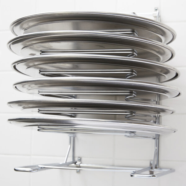A wall mounted American Metalcraft pizza pan rack with 7 slots holding pizza pans.