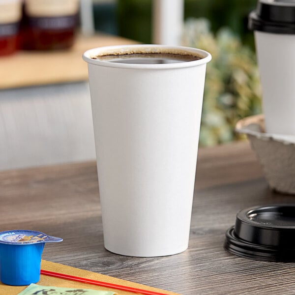 A white Choice paper hot cup filled with brown liquid on a table.