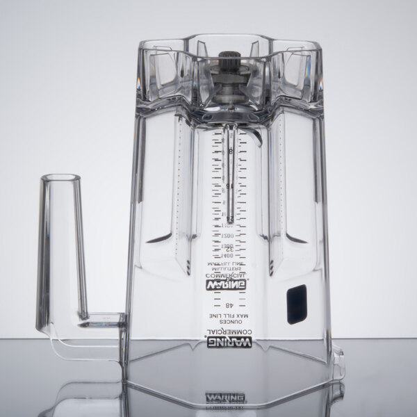A clear Waring blender jar with a measuring device.