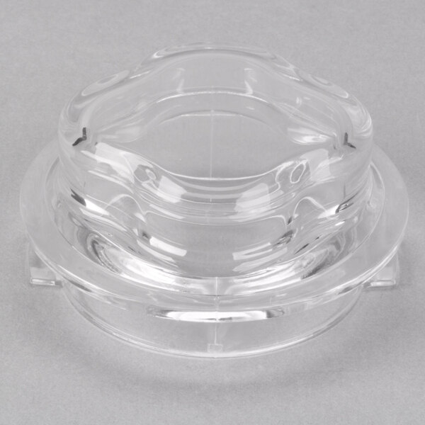 A clear plastic container with a curved edge and a Waring lid with a measuring cup on top.