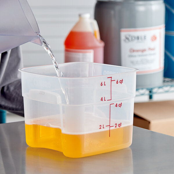 A person pouring orange Noble Chemical citrus solvent cleaner into a plastic container.