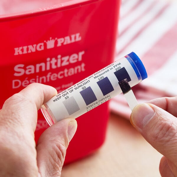 A vial of Noble CM-240 chlorine test strips with a color comparison chart, used for measuring sanitizer chlorine levels.