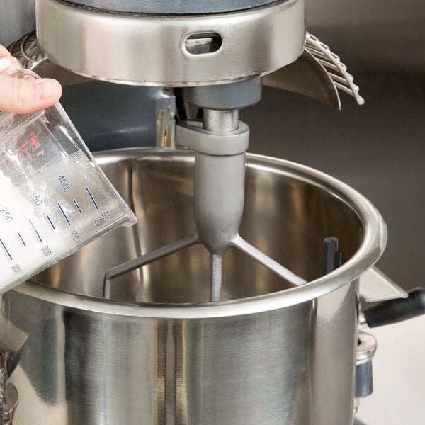 A hand holding a mixer with a flexible silicone beater in a bowl.