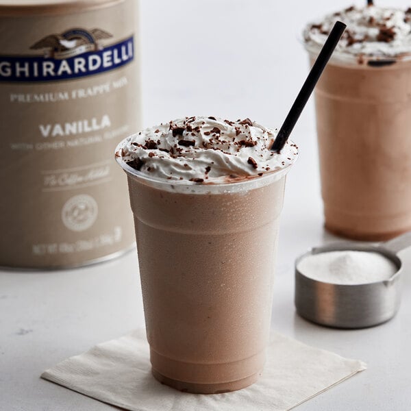 A cup of Ghirardelli Vanilla Frappe with whipped cream and chocolate chips on a counter.