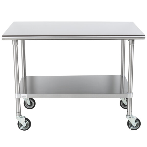 A silver metal Advance Tabco work table with wheels.