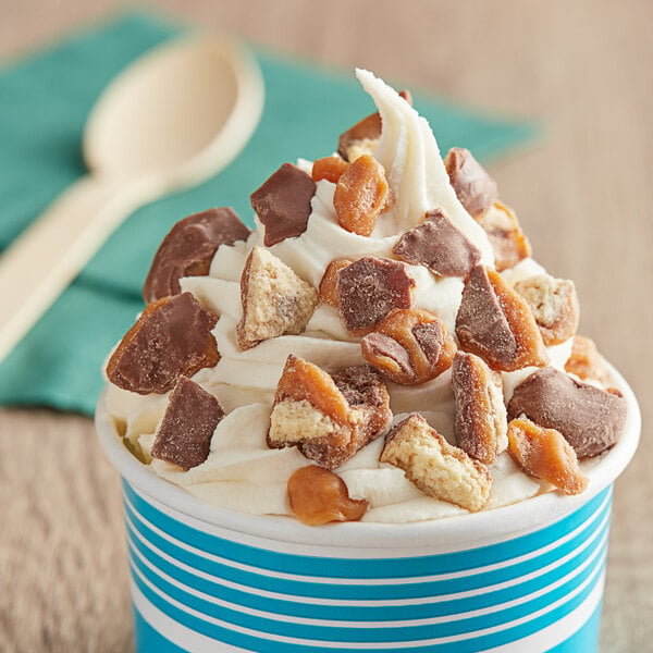 A cup of ice cream with TWIX® topping and a spoon.