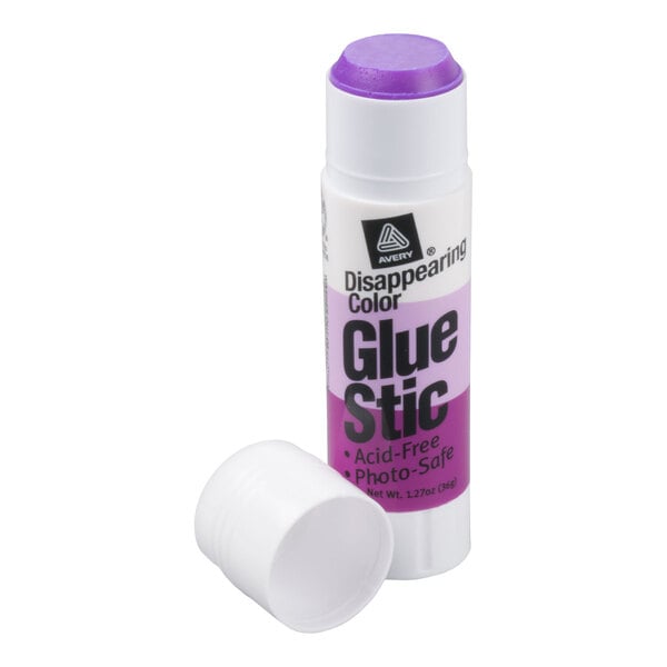 A white glue stick with a purple adhesive tip and a removed cap placed beside it.