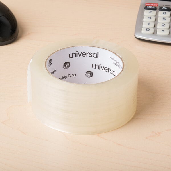 A roll of Universal clear box sealing tape on a table next to a calculator.