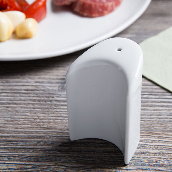 A Tuxton bright white china salt shaker on a table.