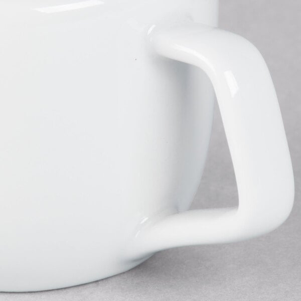 A close-up of a Tuxton bright white china creamer.