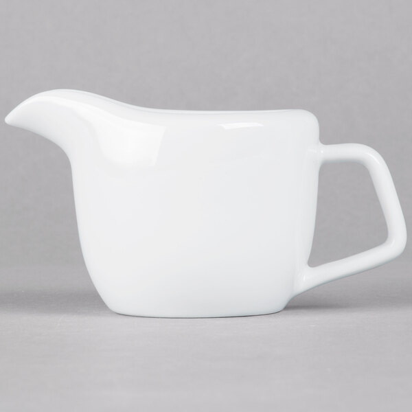 A Tuxton TuxTrendz white china creamer with a handle.