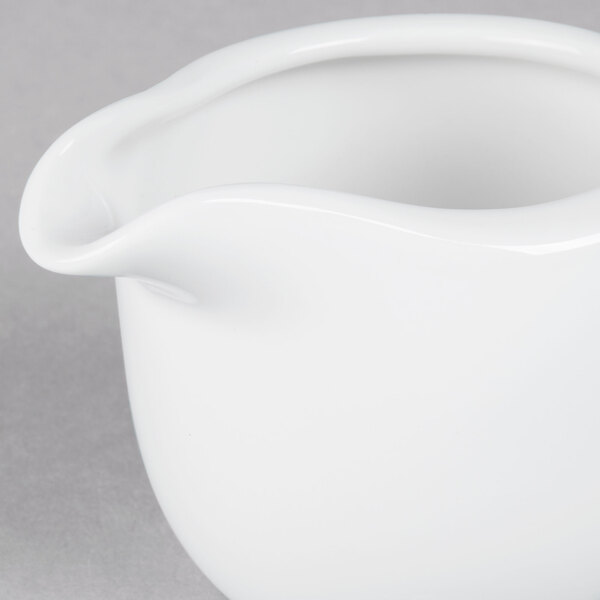 A Tuxton TuxTrendz bright white china creamer on a white surface.