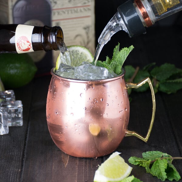 A copper mug filled with ice and a lime on a counter.