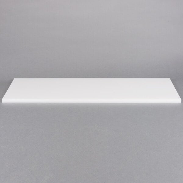 A white rectangular Delfield cutting board on a gray surface.