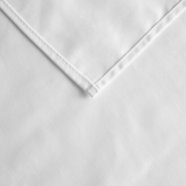 A white square tablecloth with a hemmed edge and corner.