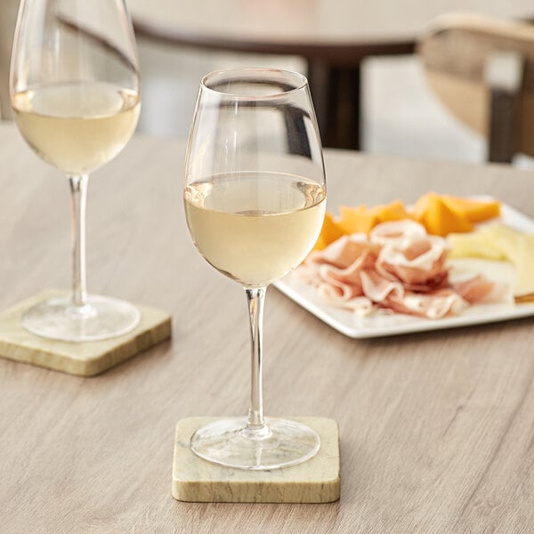 Two Acopa Select Blanc wine glasses of white wine on a table.