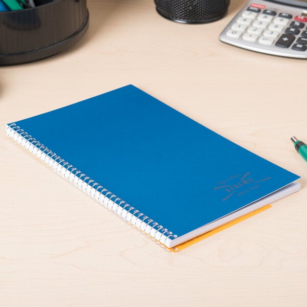 A blue National College Rule 1 Subject Wirebound Notebook with a spiral binding on a desk.