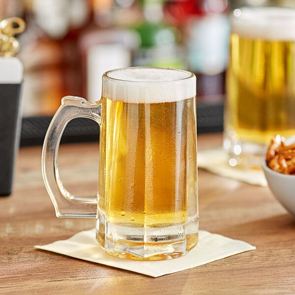 A table with a bowl of chips and an Acopa beer mug full of beer on it.